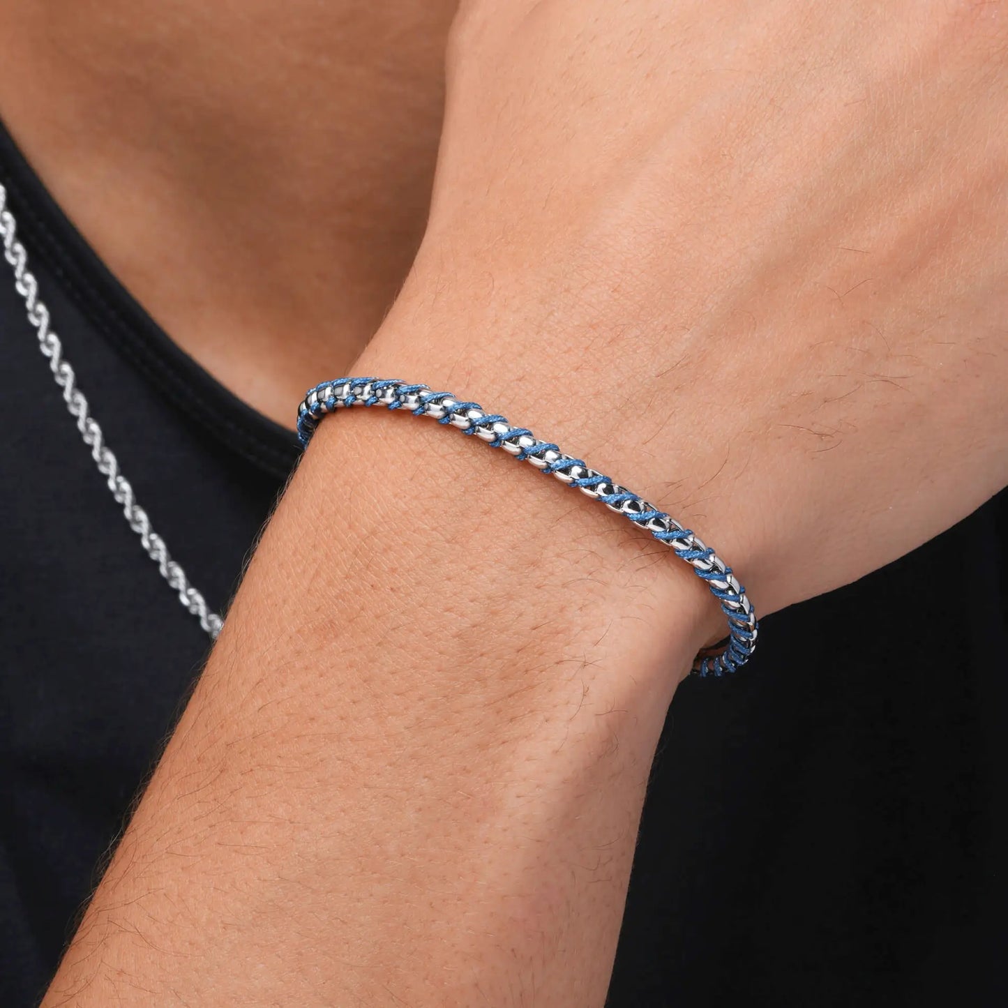Silver / Blue || Close up of a wrist wearing a slim silver chain bracelet with navy blue accents on a black shirt background