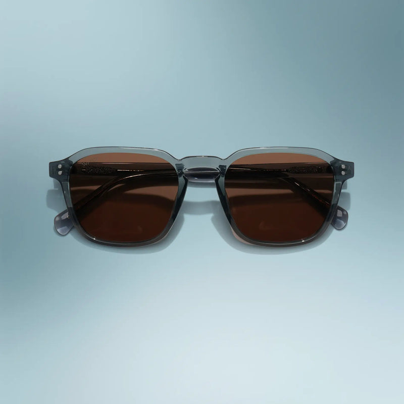 WMP Eyewear Francis sunglasses in Crystal Stone Blue, featuring a translucent blue-gray frame with brown-tinted lenses.