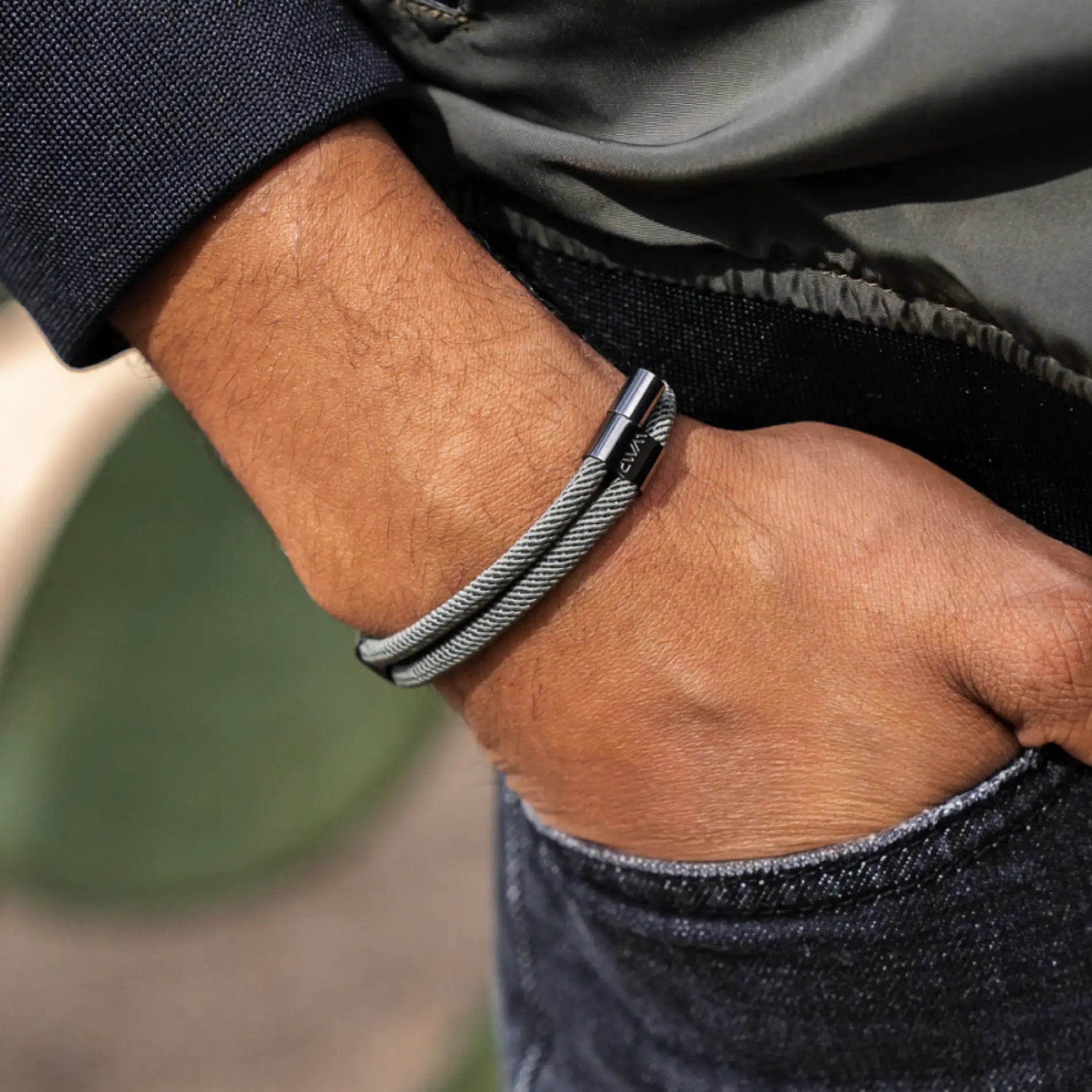 Olive Green / Gunmetal || Man’s wrist wearing a sleek gray Knox Bracelet with twisted metal cable design and clasp detail outdoors