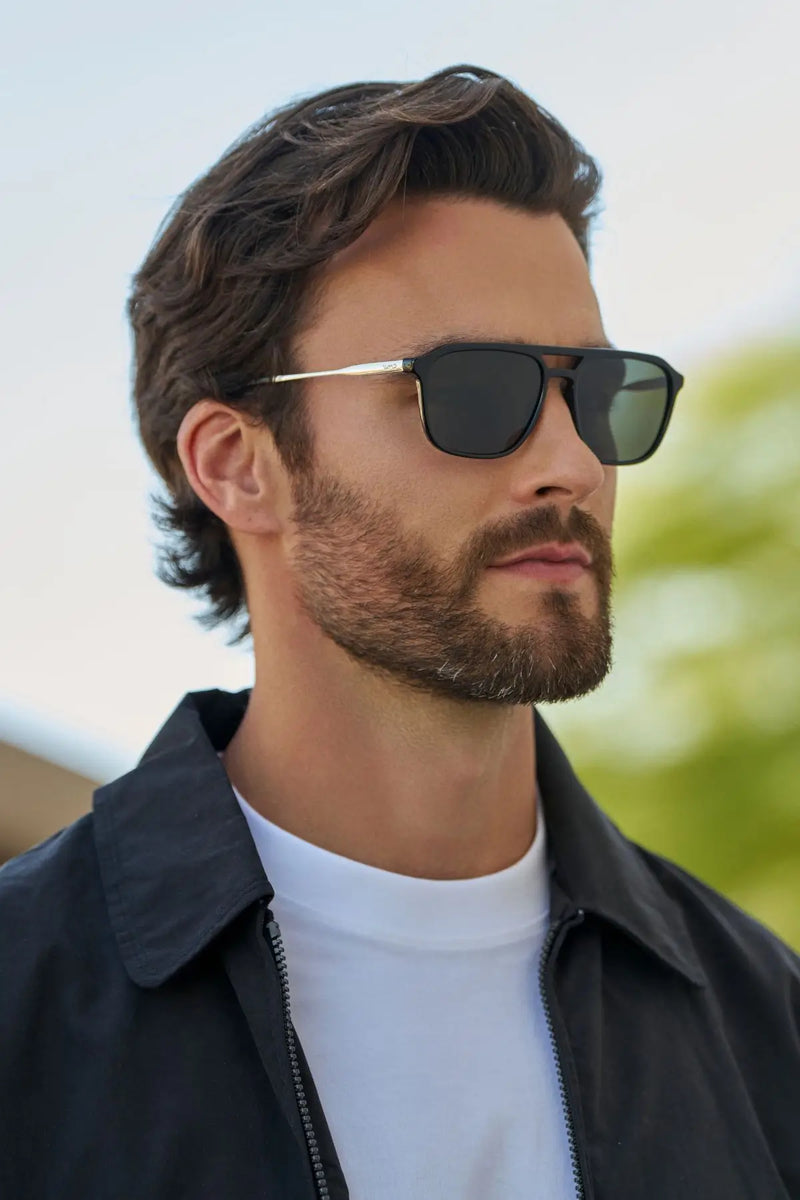 Model wearing WMP Eyewear Gage sunglasses in Black, featuring a rectangular aviator frame with slim metal temples and dark black lenses.