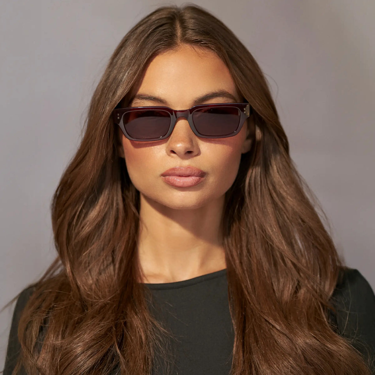 Red Garnet / Brown Gold Gradient Lens || Model wearing Women's Rectangular Polarized Sunglasses with Red Garnet frame and Brown Gold Gradient Lens against a grey background