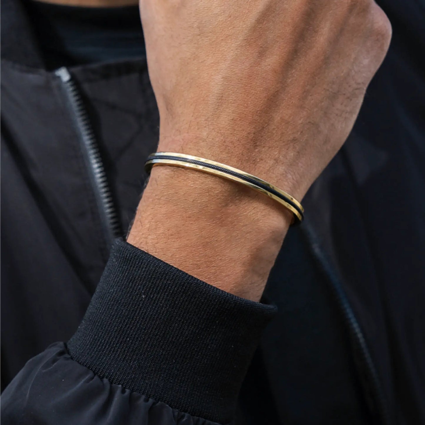 Onyx Black / Gold || Slim bangle with black and gold finish worn on wrist over black jacket cuff
