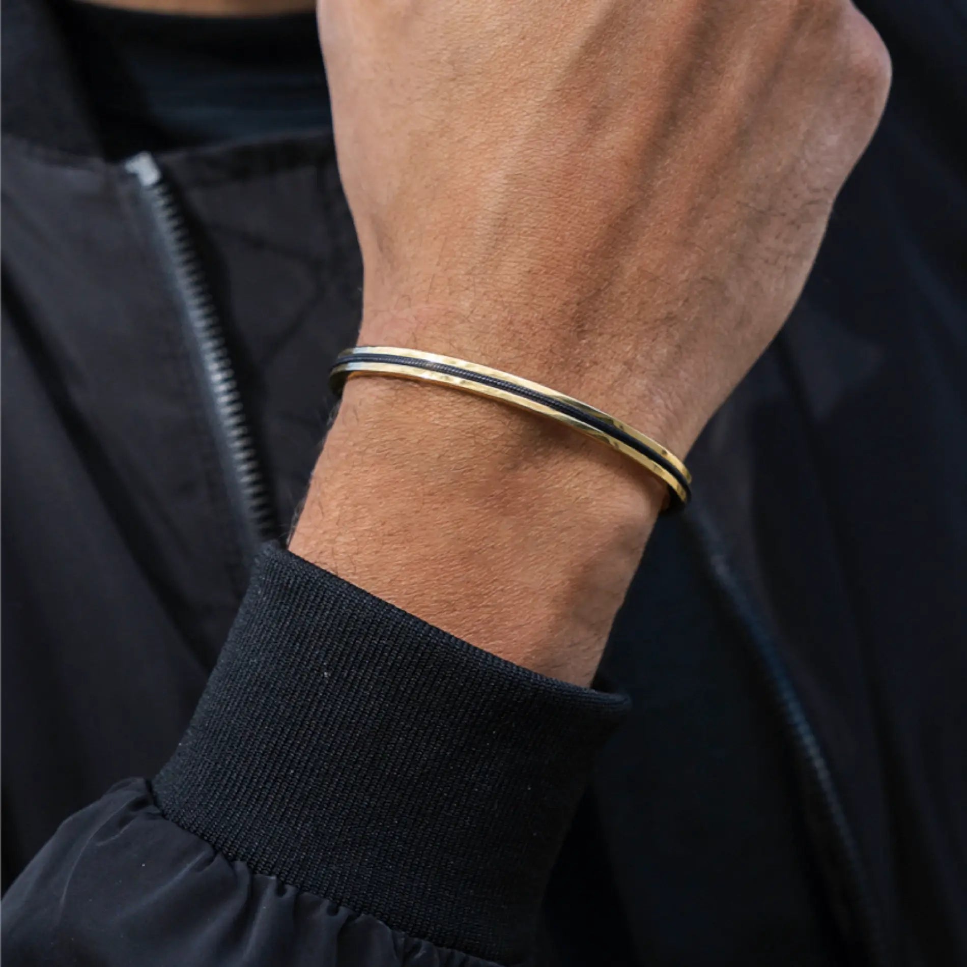 Onyx Black / Gold || Slim bangle with black and gold finish worn on wrist over black jacket cuff