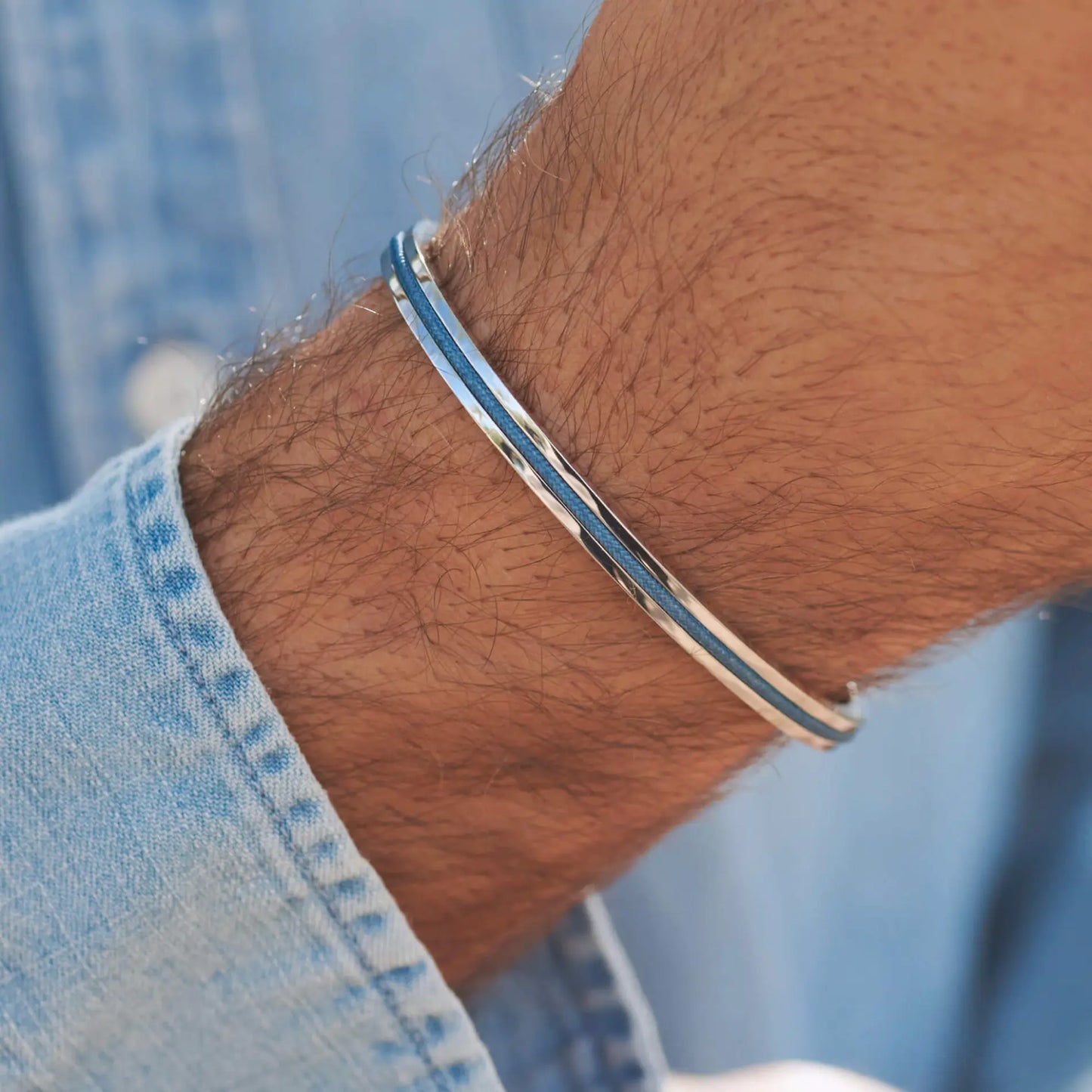 Silver / Blue || Close up of a wrist wearing a slim silver and blue double-band bracelet over light denim fabric