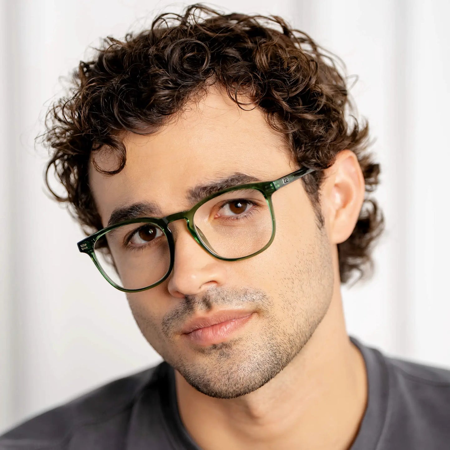 Close-up of man wearing vintage-inspired square green eyeglasses with tapered rims and metal accents