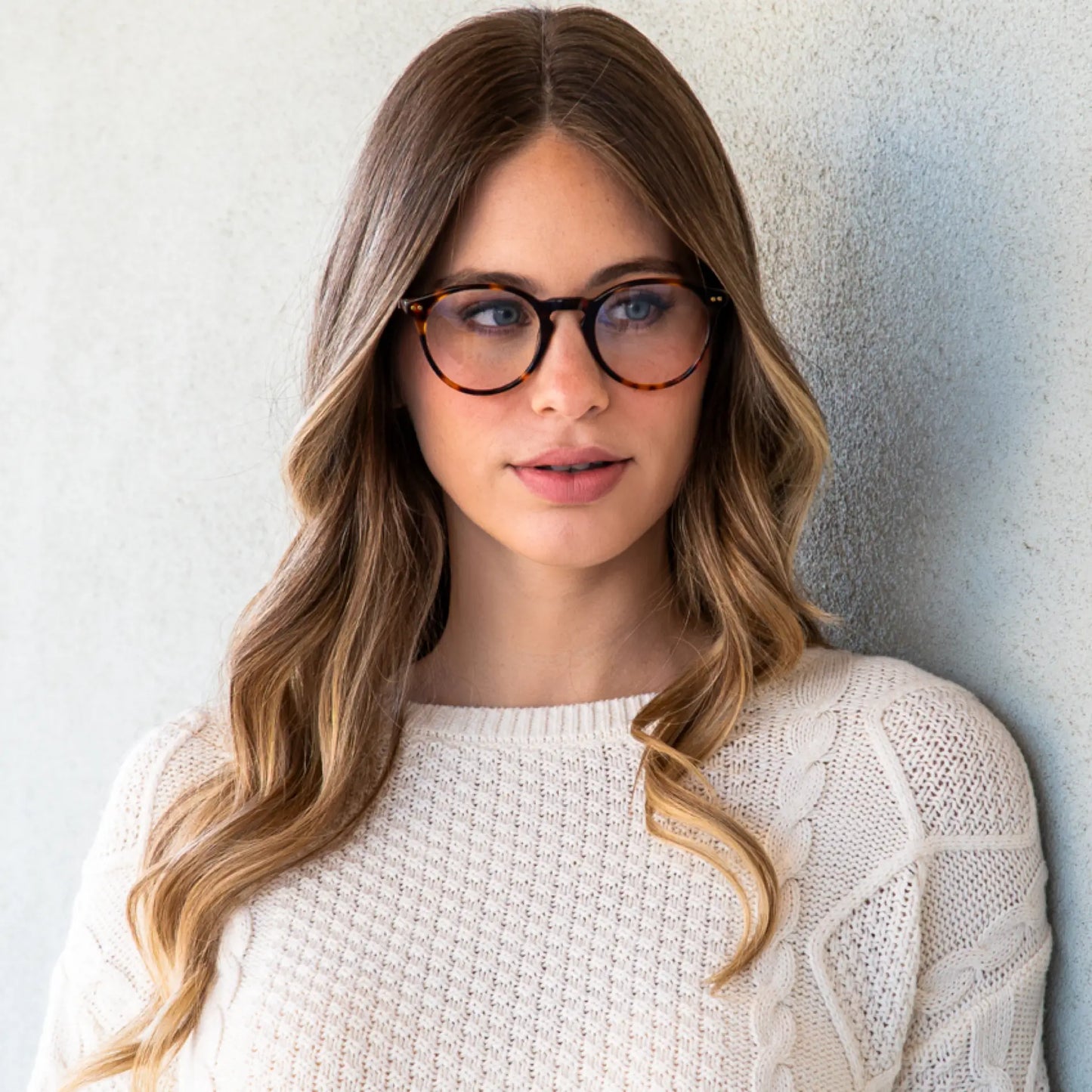Tortoise Brown || Woman with long wavy hair wearing tortoise shell round frame blue light glasses standing against light textured wall