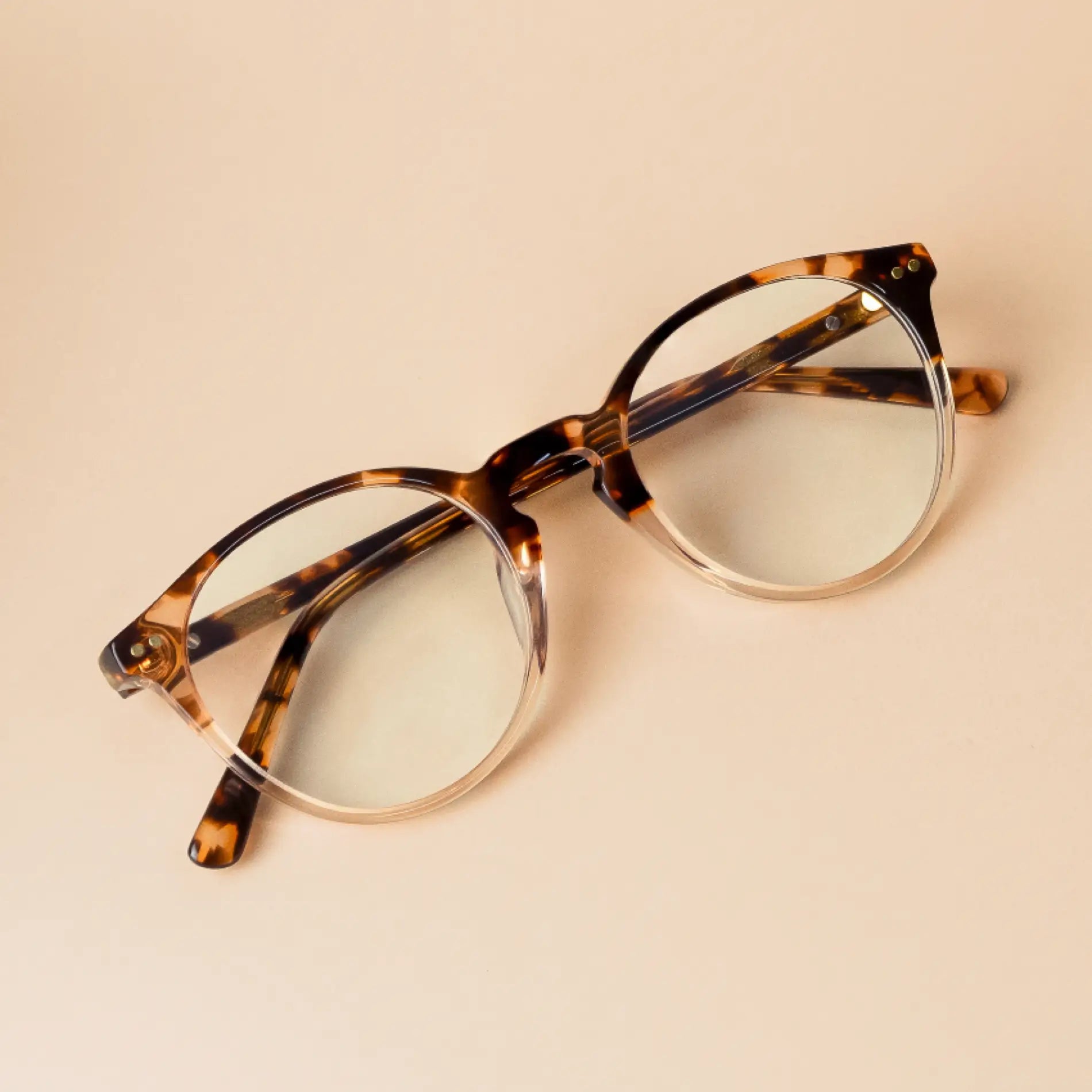Crystal Brown Tortoise || Owen blue light glasses with semi-transparent tortoise shell round frame resting on beige background