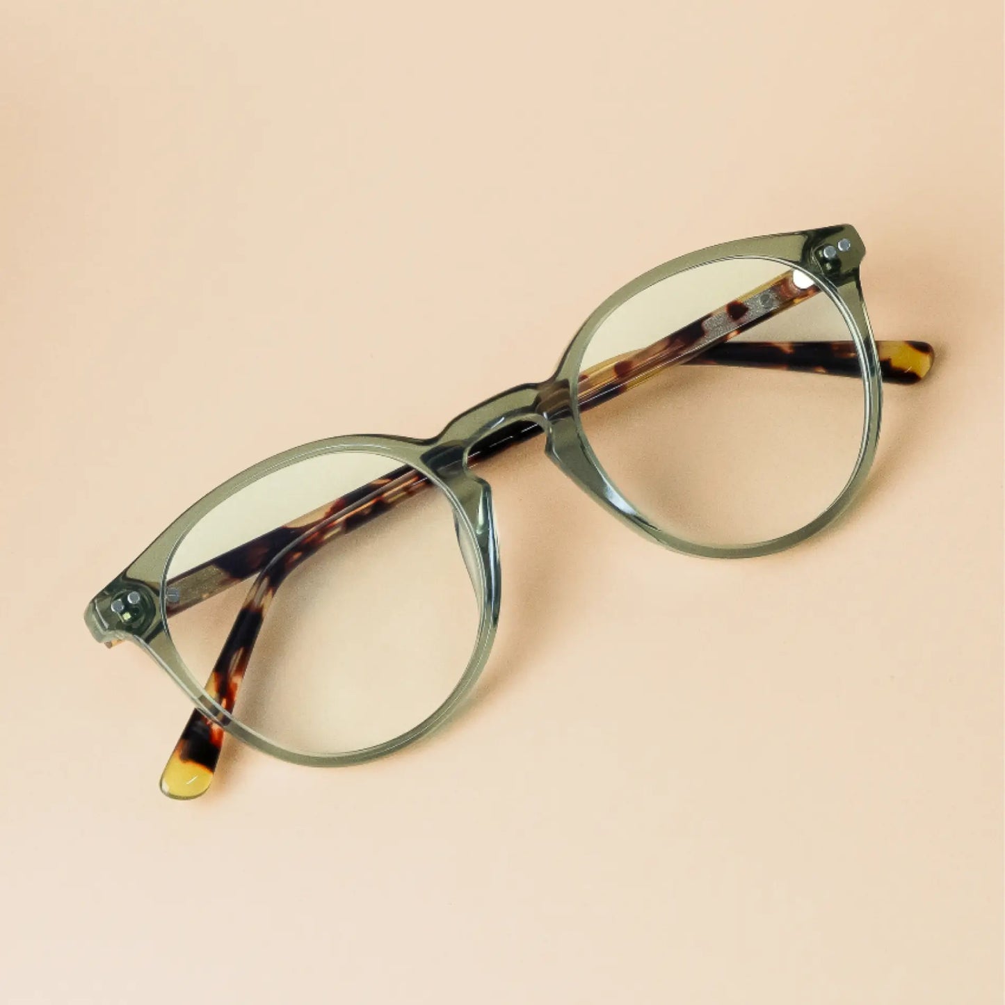 Tortoise Crystal Green || Transparent green rounded frames with tortoise shell arms blue light filtering glasses on beige background