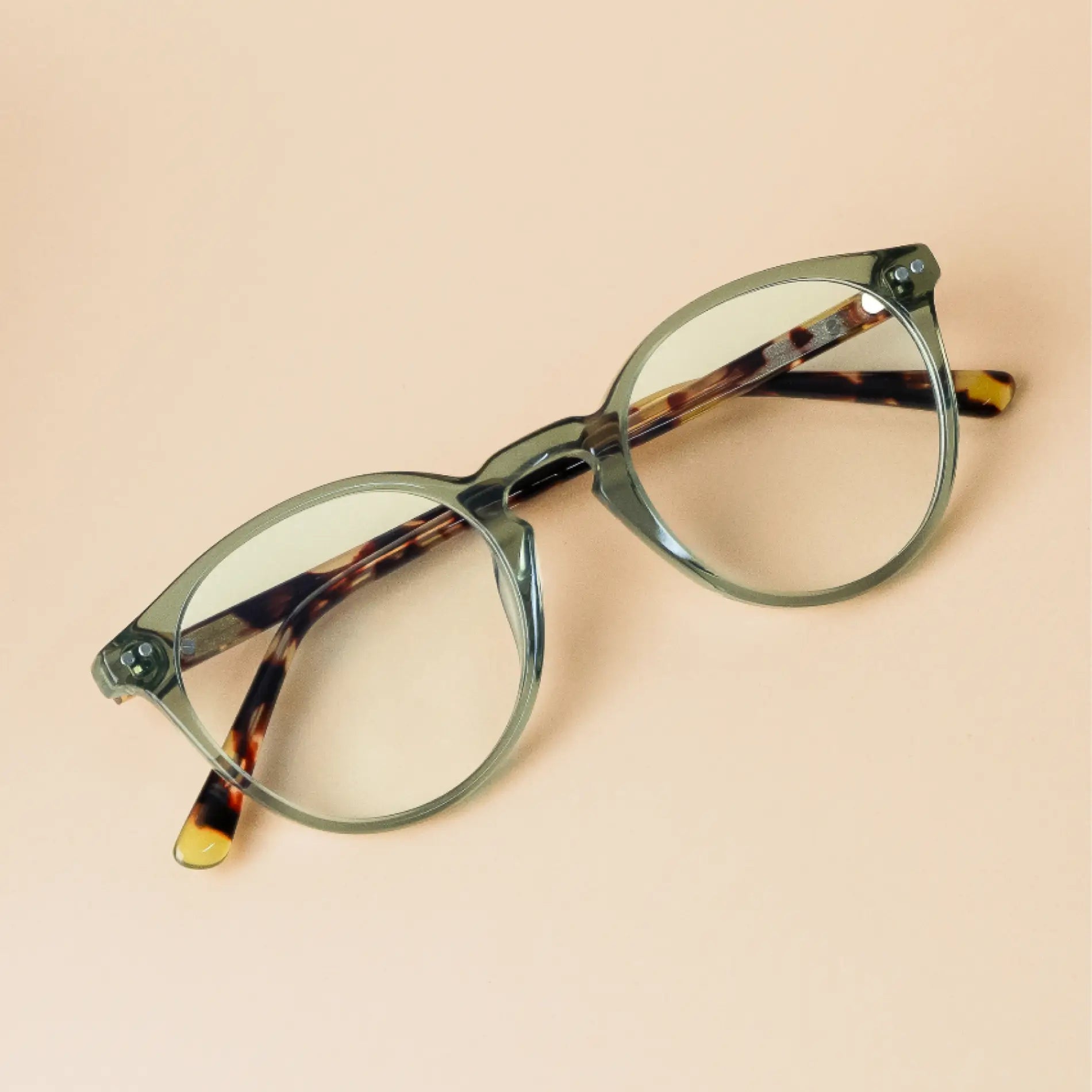 Tortoise Crystal Green || Transparent green rounded frames with tortoise shell arms blue light filtering glasses on beige background