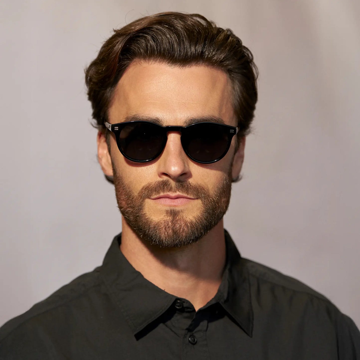 Black / Triple Black Lens || Front view of man wearing Round Polarized Sunglasses with Black Frame and Black Lens against a grey background