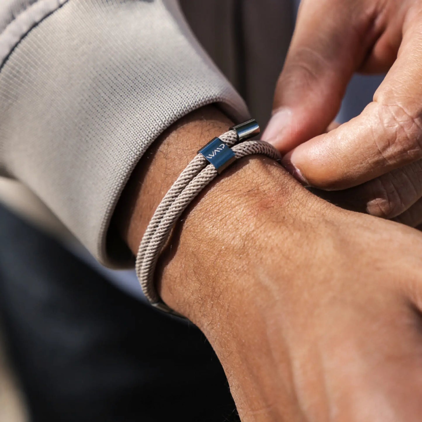 Sand / Gunmetal || Close up of wrist showing beige braided Knox Bracelet with polished metal clasp being adjusted in natural lighting