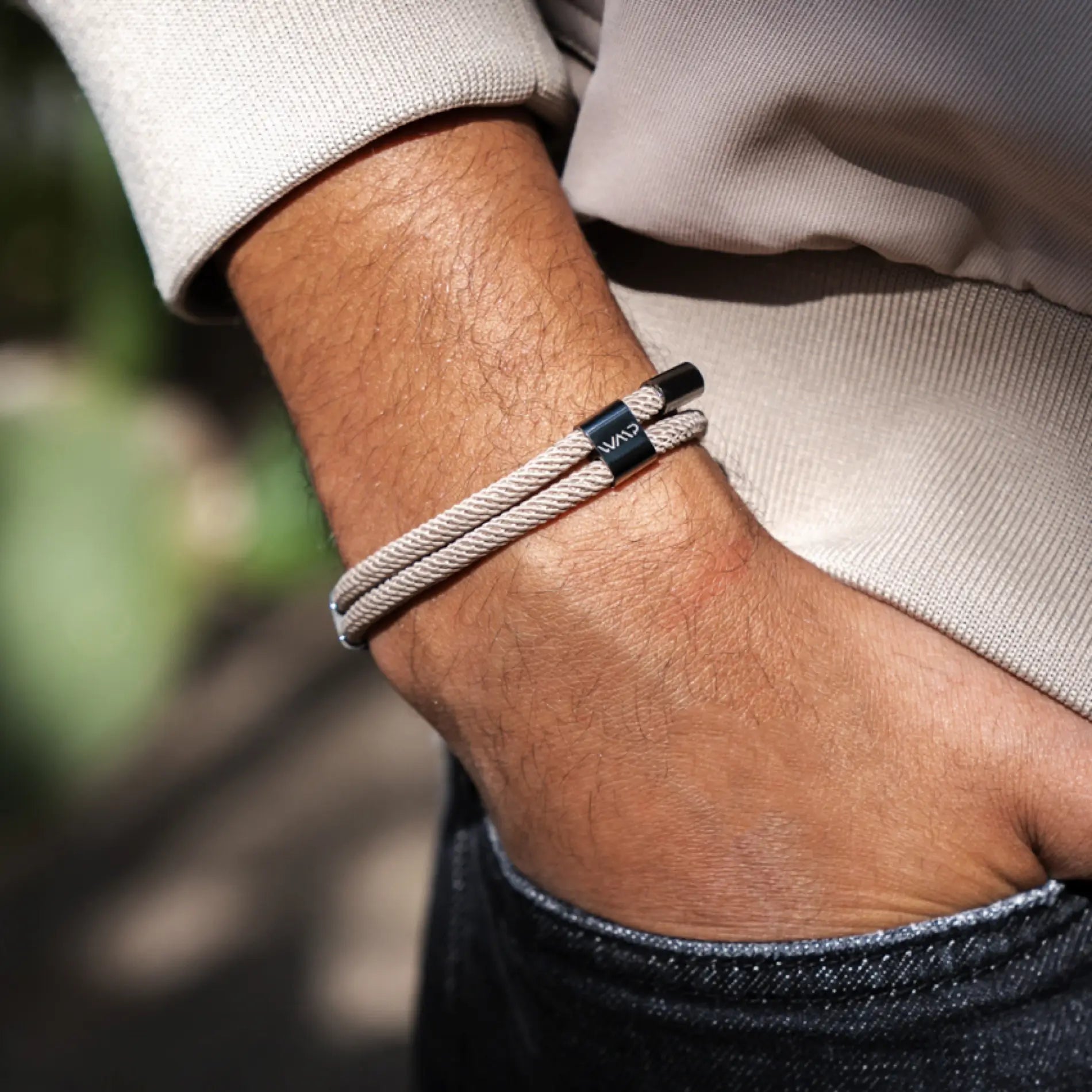 Sand / Gunmetal || Close up of wrist wearing a beige twisted rope Knox Bracelet with black metal clasp resting hand in denim pocket outdoors