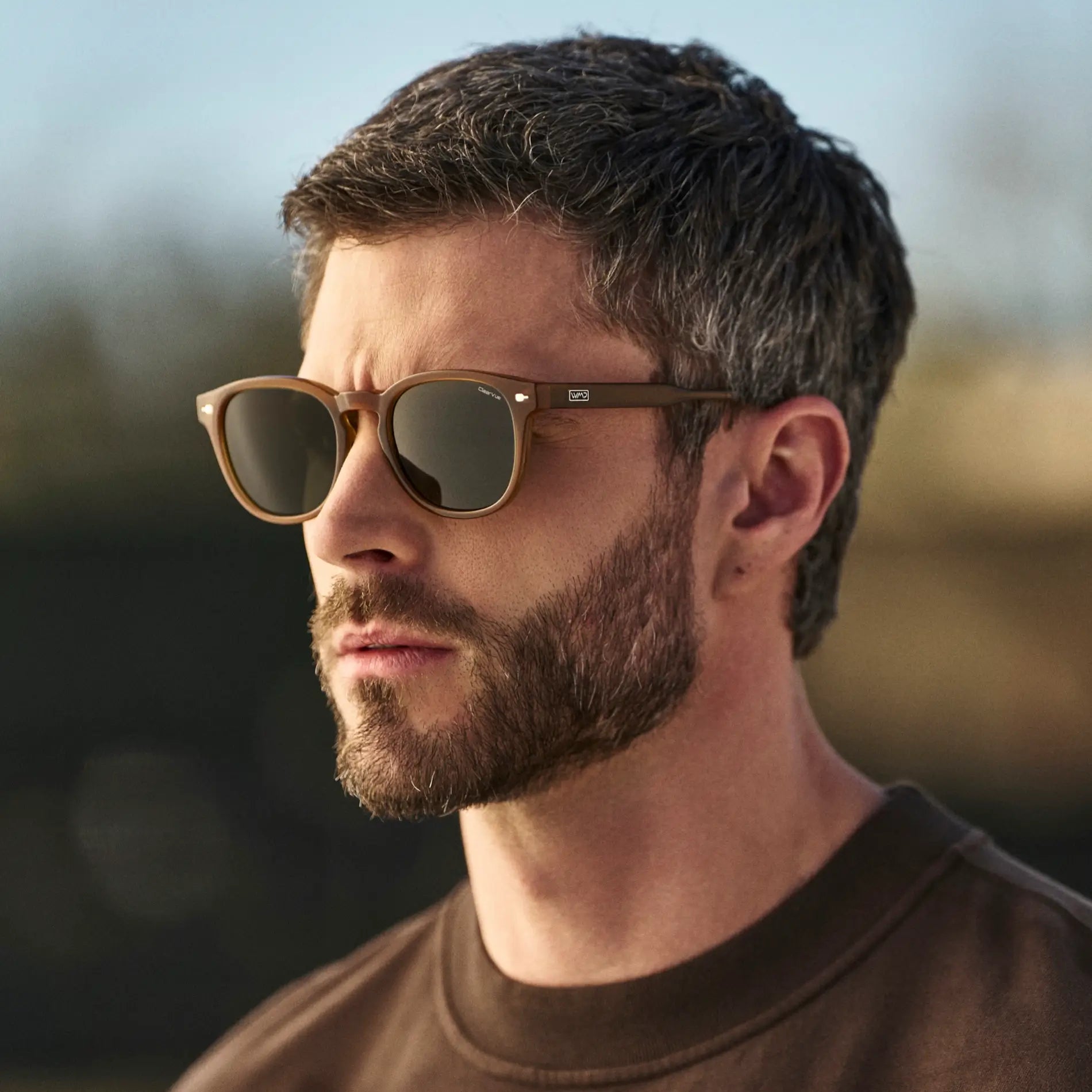 Dune Brown / Smoke Green Lens || Man wearing Round Sunglasses with Dune Brown Frame and Smoke Green Oval Lens outdoors