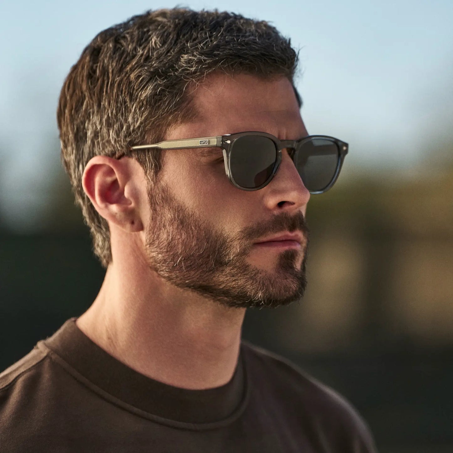 Sage Green / Black Lens || Man wearing Round Sunglasses with Sage Green Frame and Black Oval Lens in natural light