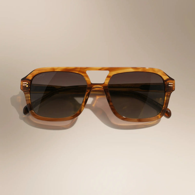 WMP Eyewear Sydney sunglasses in Crystal Brown Grain, featuring a translucent amber-brown aviator-style frame with dark tinted lenses.
