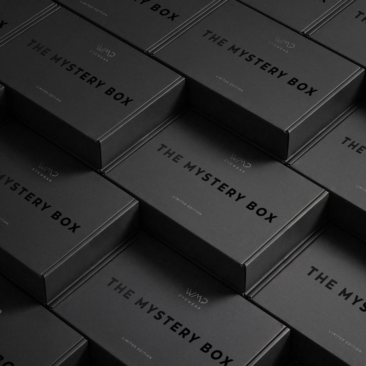 Women || Multiple matte black rectangular boxes stacked at an angle, each printed with the text 'THE MYSTERY BOX' and a small 'WMP' logo.