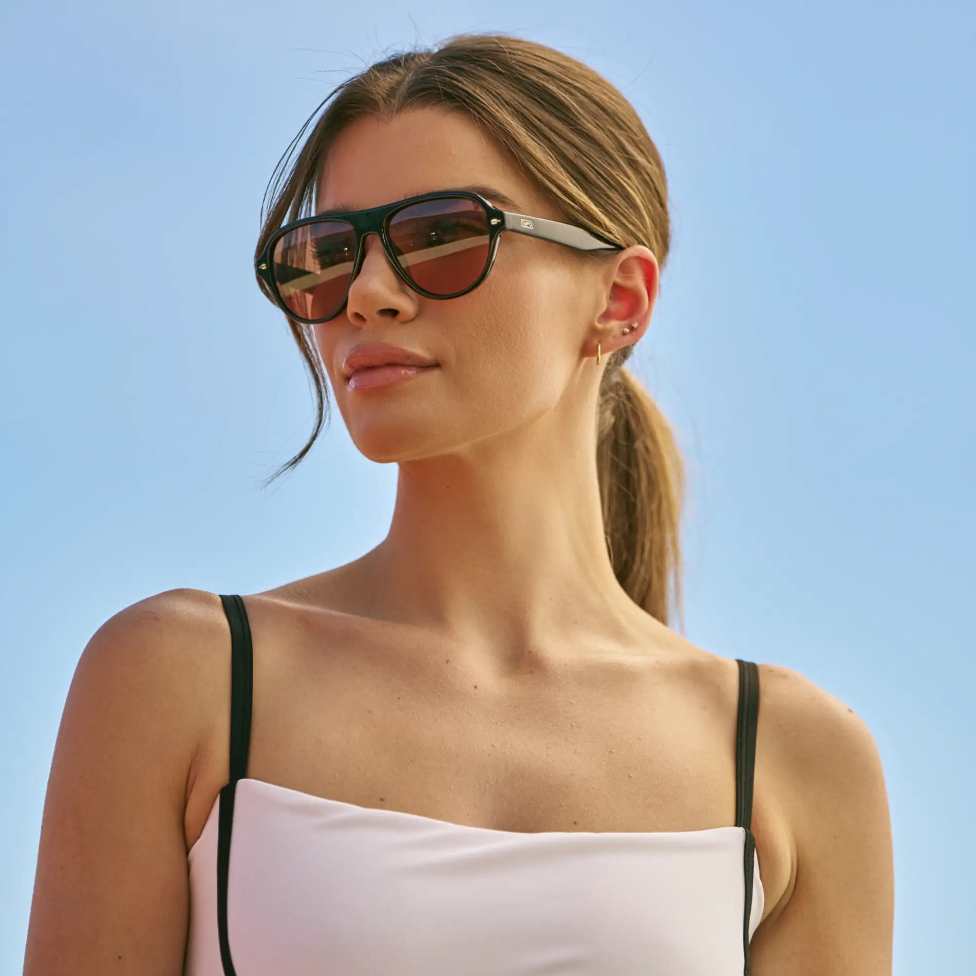Black / Tinted Red Lens || Woman wearing Rounded Aviator Sunglasses with Black Frame and Red Tinted Lenses outdoors