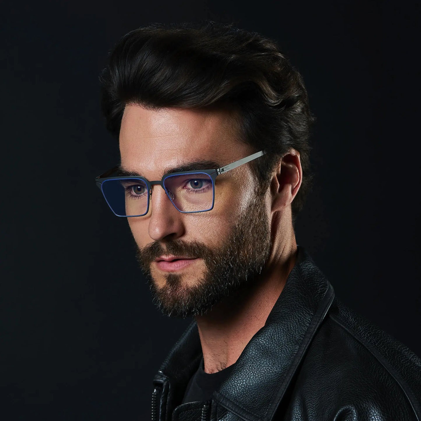 Matte Black || Zev blue light glasses with slim black metal frames and rectangular clear lenses worn by bearded man with a black background 