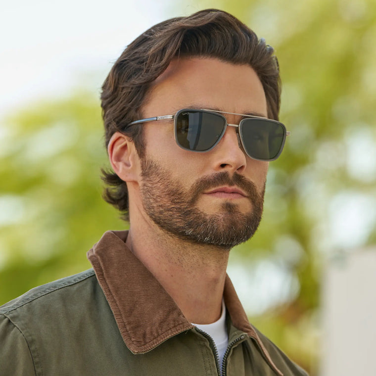 Model wearing WMP Eyewear Weston sunglasses in Smoke Grey, featuring a sleek rectangular frame with slim silver metal temples and smoke green lenses.