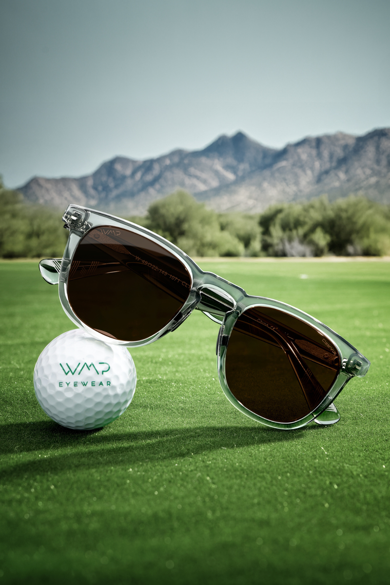 Sunglasses and golf ball on a golf course with mountains in the background