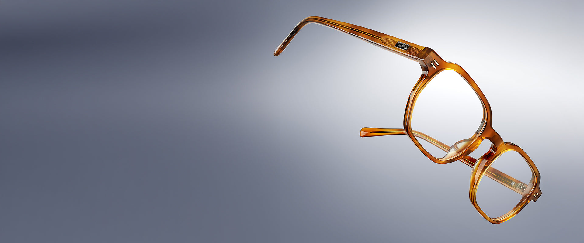 Honey tortoise-colored acetate eyeglass frames shown at an angle, with rectangular lenses and slim temples, isolated against a neutral gradient background.