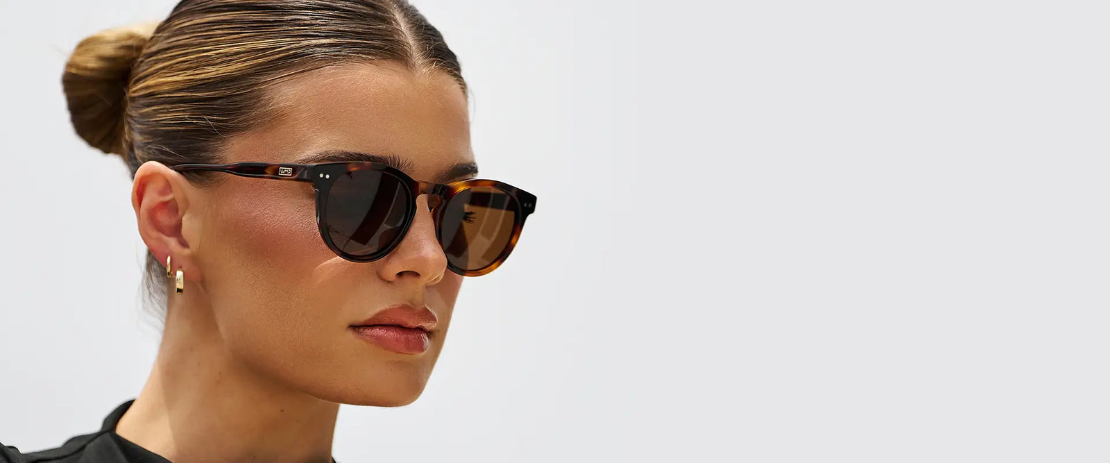 Model wearing Tate sunglasses in Brown Tortoise in a close-up outdoor lifestyle photo.