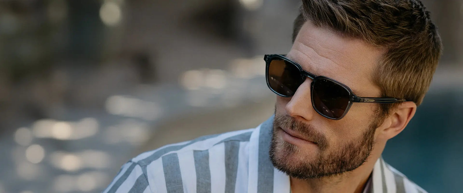 Man wearing WMP Eyewear Francis sunglasses in crystal stone blue with brown lenses poolside